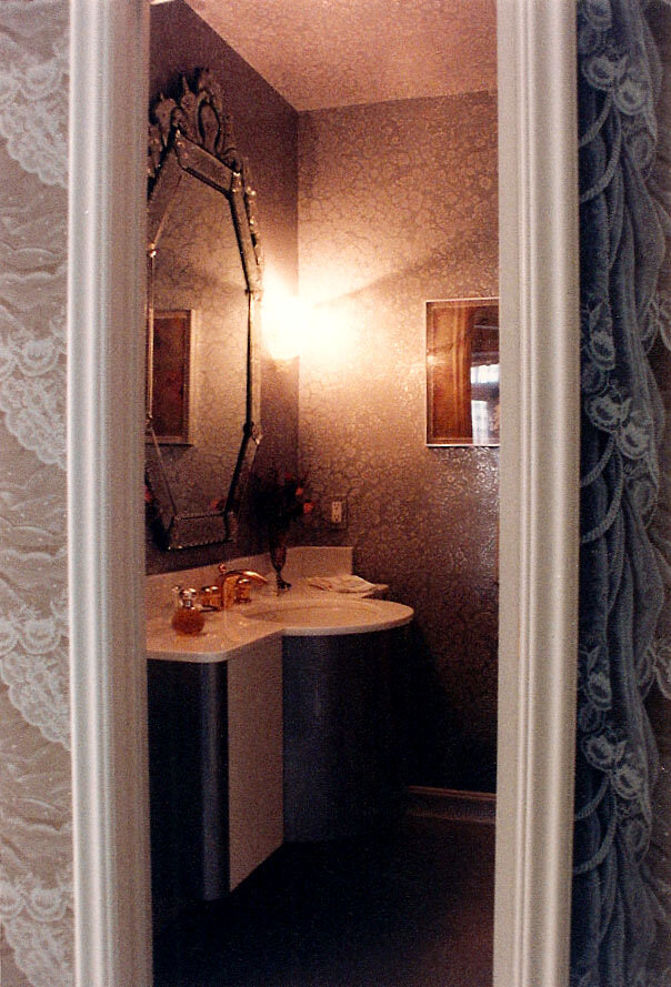 Narrow powder room with a corner sink and an ornate etched glass mirror