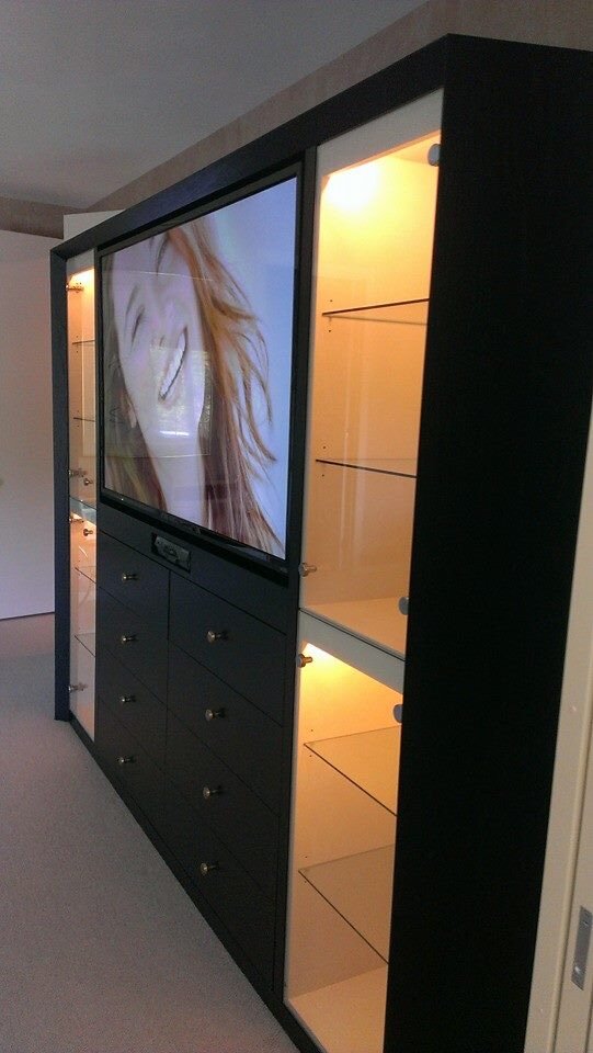 Side view of a black entertainment center with lit glass display shelves