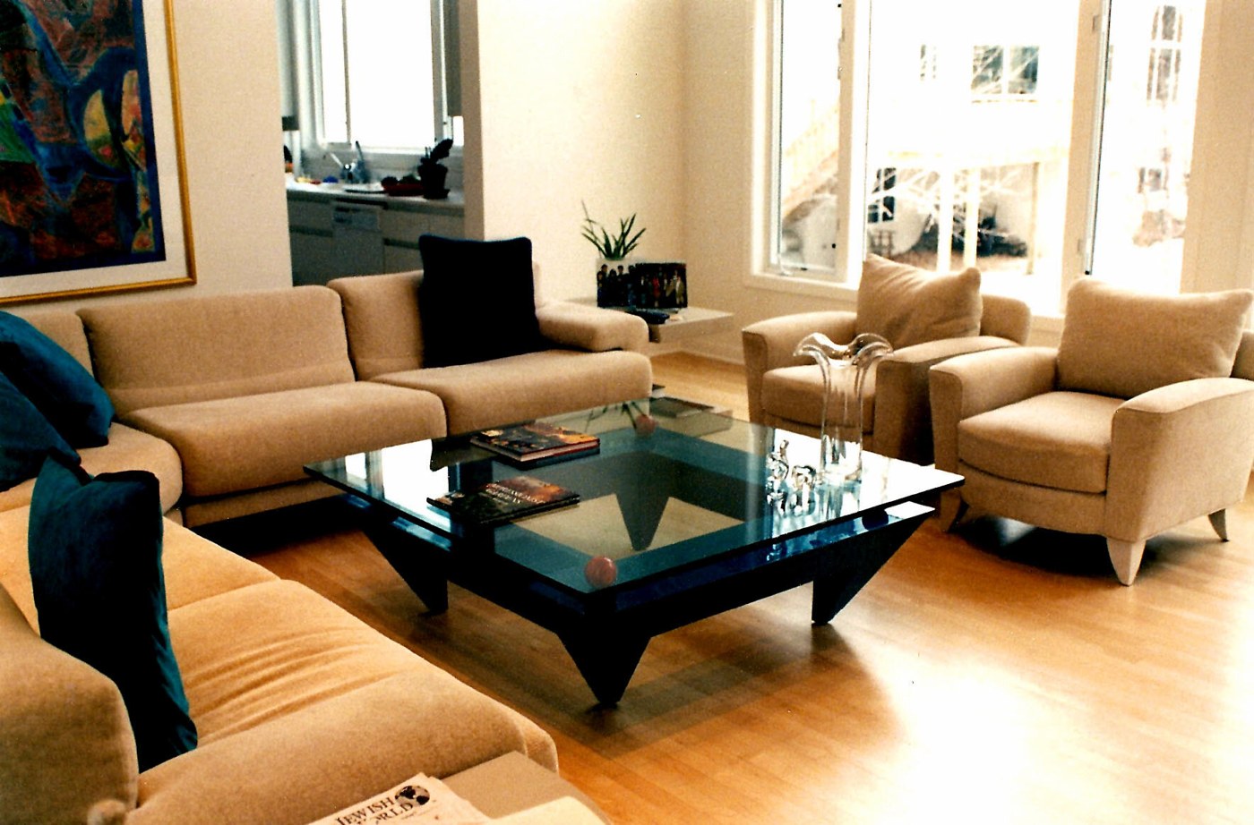 Sunlit living room with a custom glass-top coffee table on a dark angular base