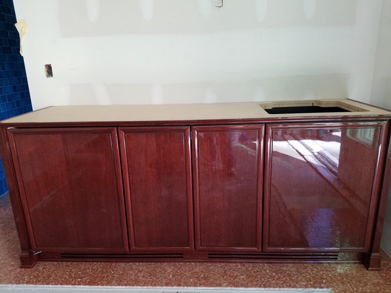 Red cherry-finish bar cabinets with raised panel doors and a light countertop