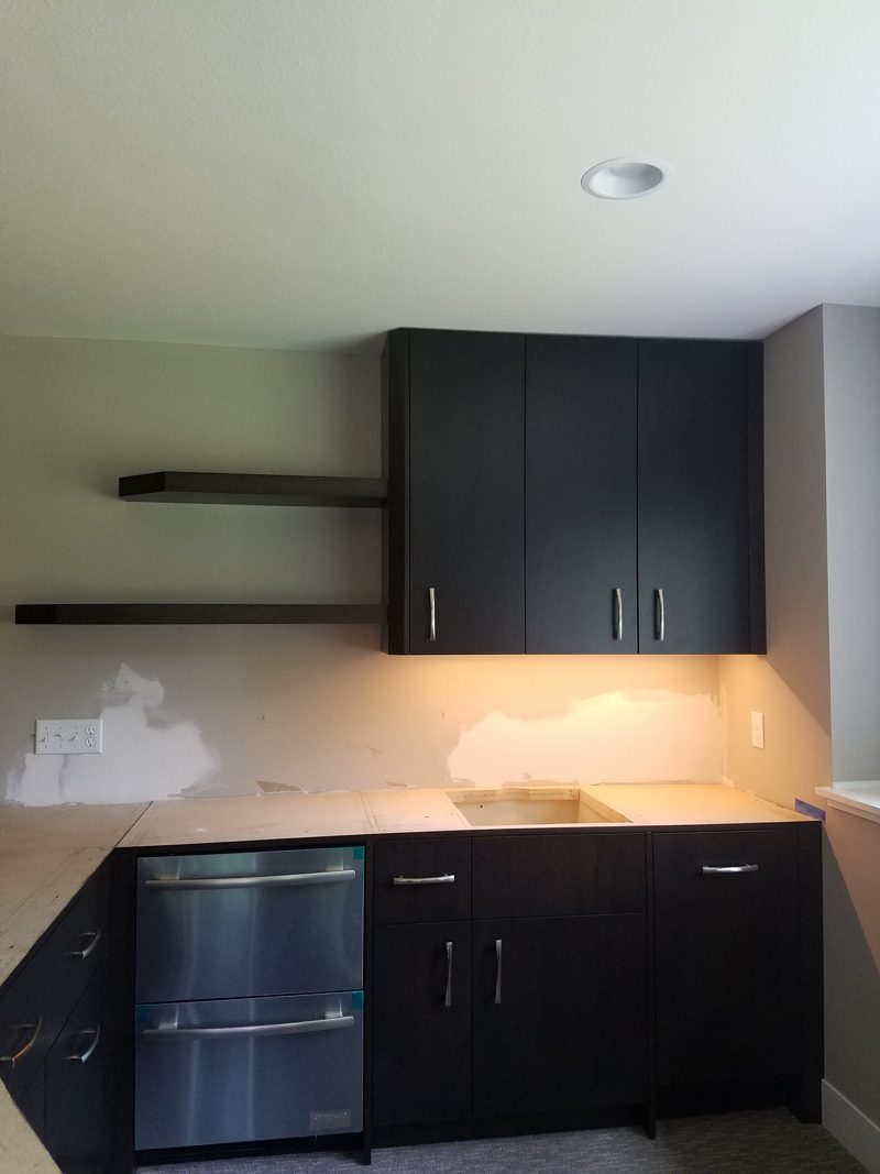 Dark wood bar cabinets with a beverage fridge and floating shelves