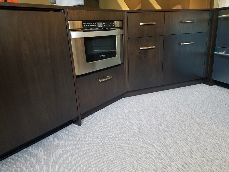 Dark wood bar cabinetry with a built-in microwave drawer and corner cabinets