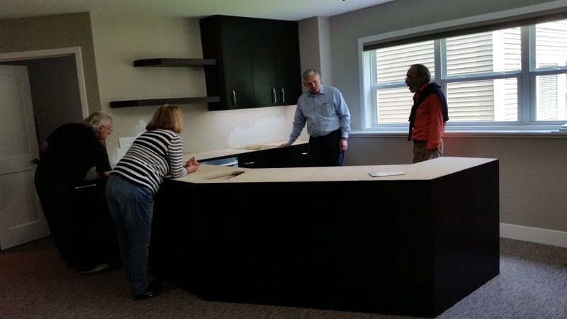 Dark L-shaped bar counter being reviewed in a finished basement