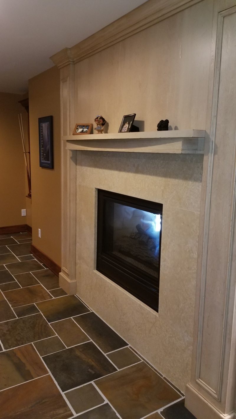 Light plaster fireplace surround with a floating mantel on slate tile