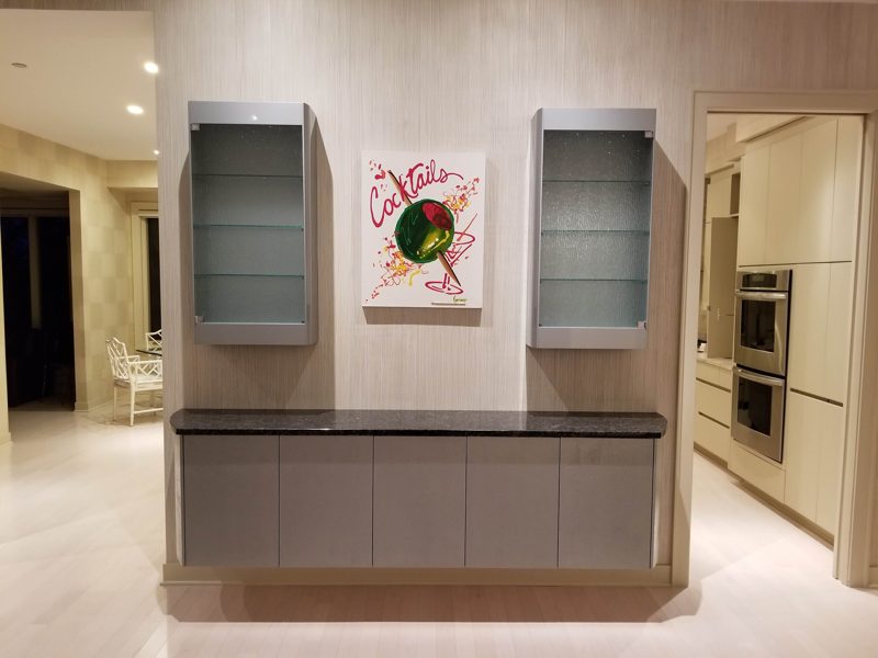 Floating gray bar cabinet with a black top and two glass wall cabinets