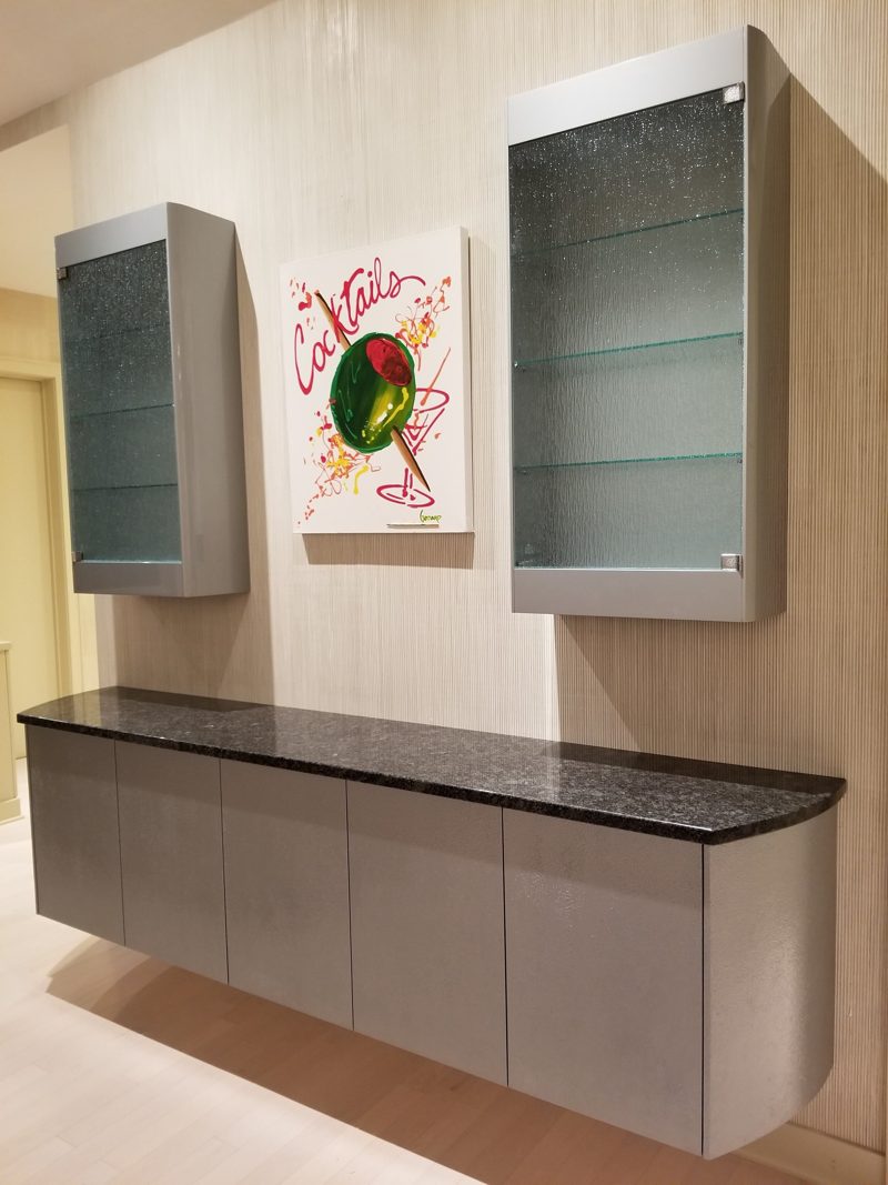 Floating gray bar cabinet with dark granite top below glass display cabinets