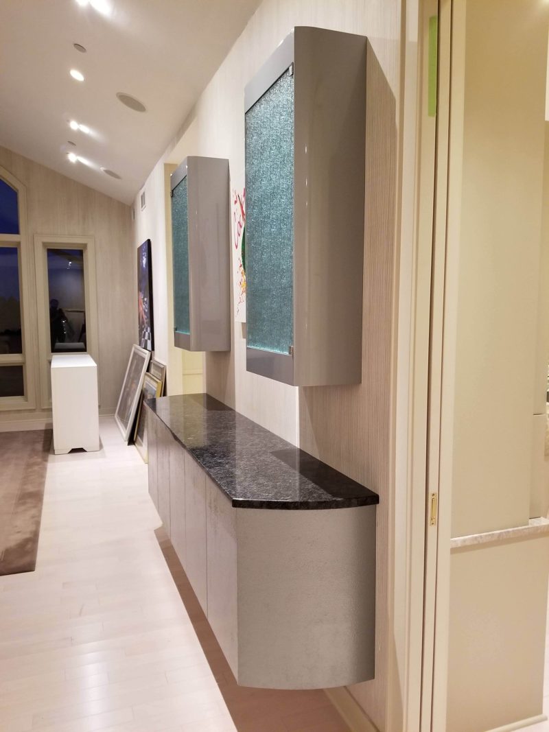 Side view of a floating gray bar cabinet with wall-hung glass cabinets