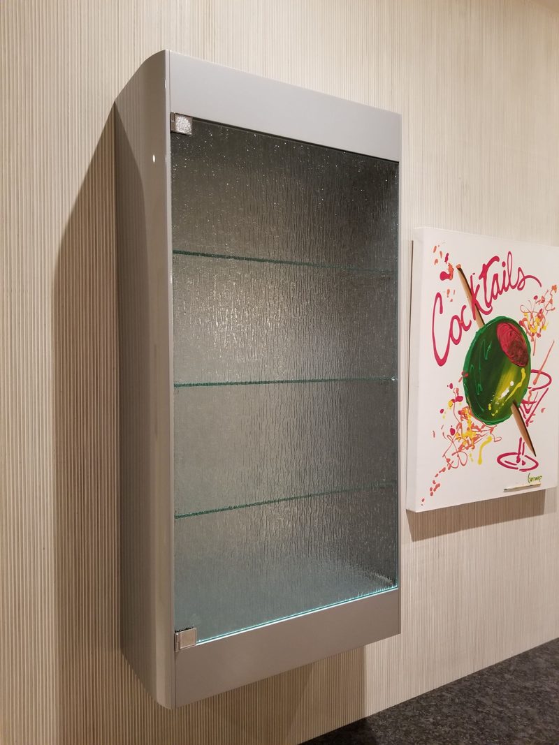 Close view of a gray wall cabinet with a glass door and shelves