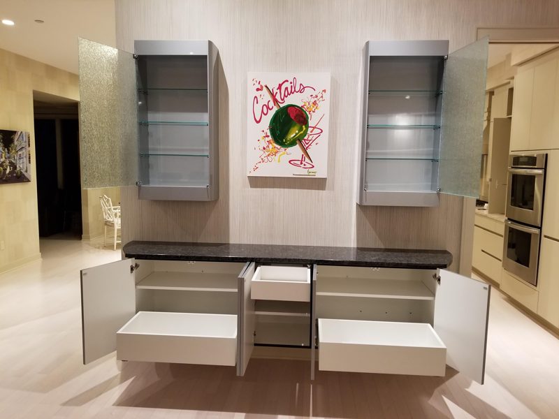 Gray bar cabinet with doors open to reveal pullout drawers and shelves