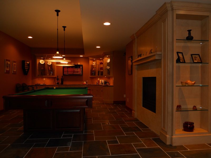 Lower-level bar and fireplace wall with lit built-in shelves near a pool table