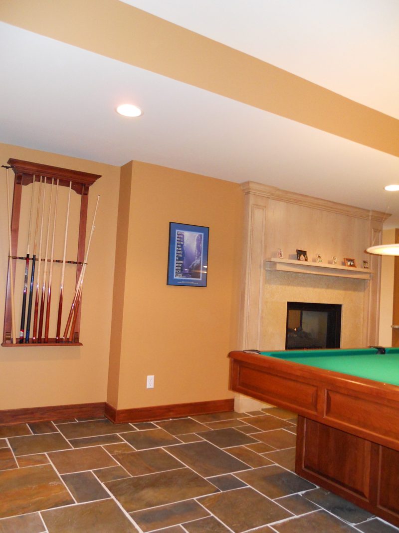 Wall-mounted wood cue rack near a pool table and fireplace
