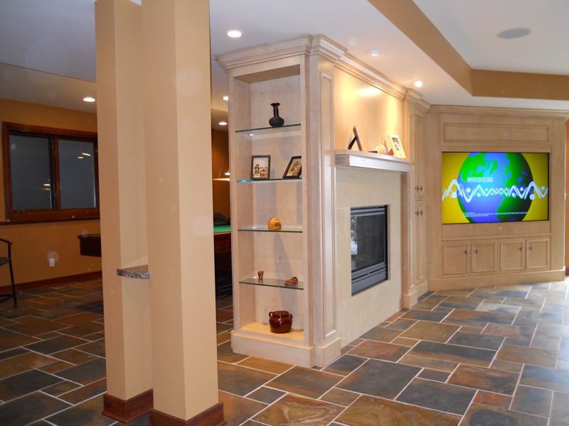 Built-in lighted shelving and fireplace surround beside a media wall