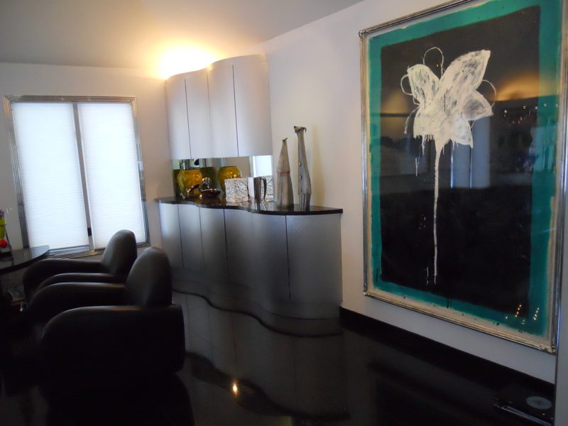 Curved white wall cabinet and wavy silver lower cabinet with a dark top