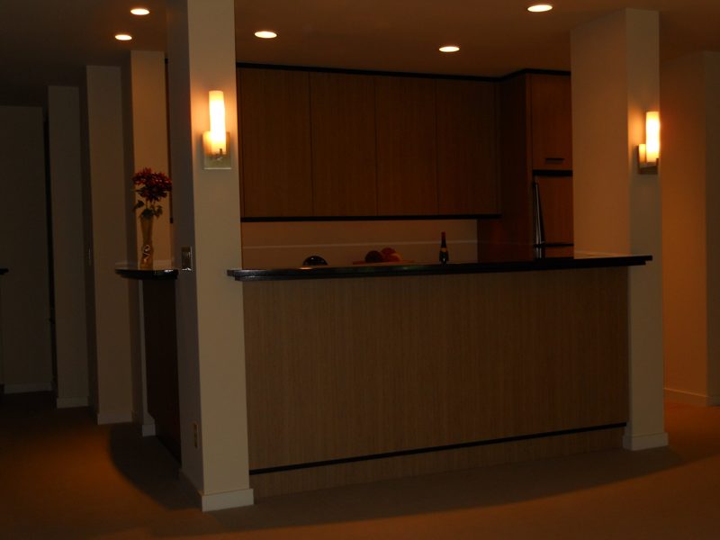 Wood-grain bar counter with a black top and wall sconces