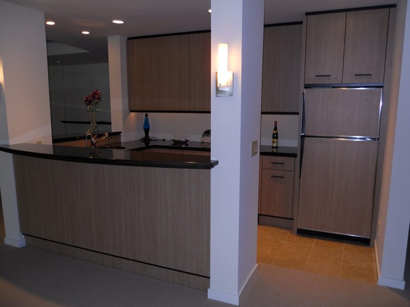 Wood-grain bar with a paneled refrigerator and dark countertop