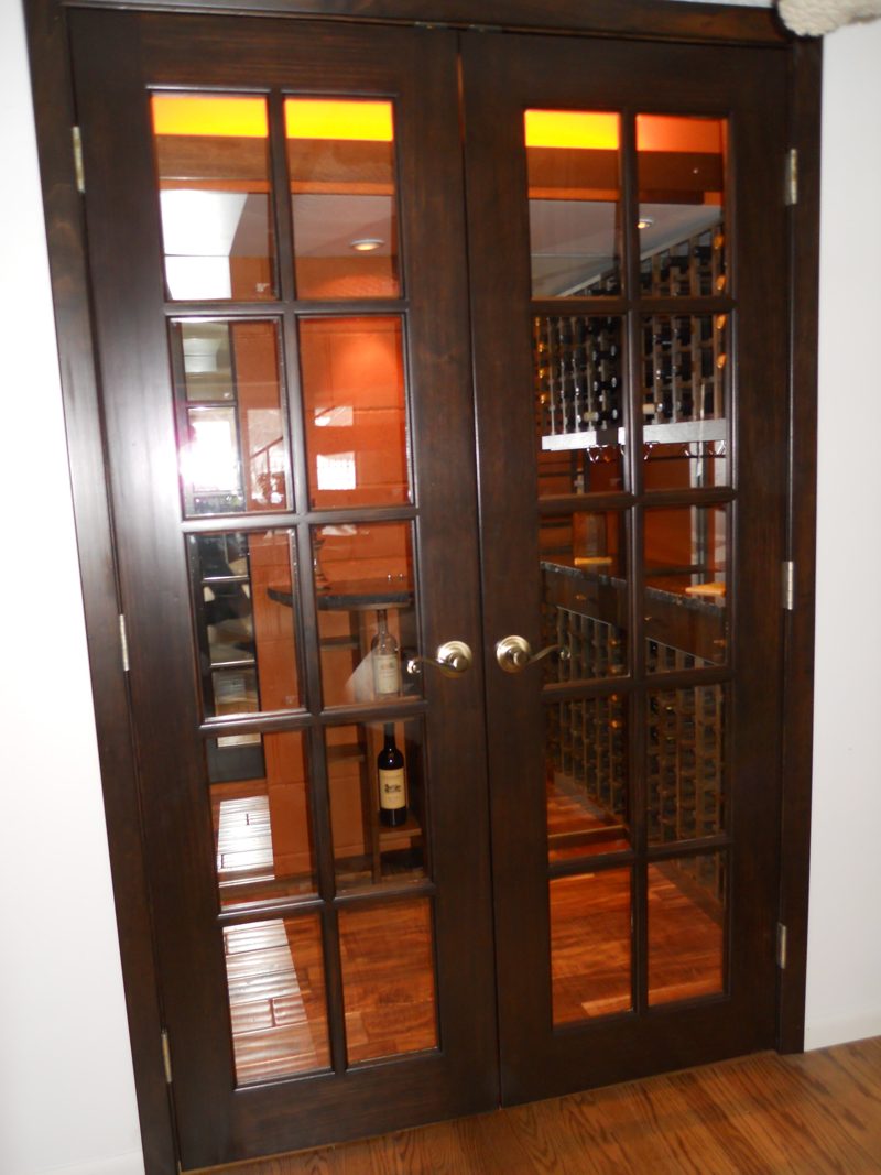 Dark wood double French doors with glass panes into a wine room