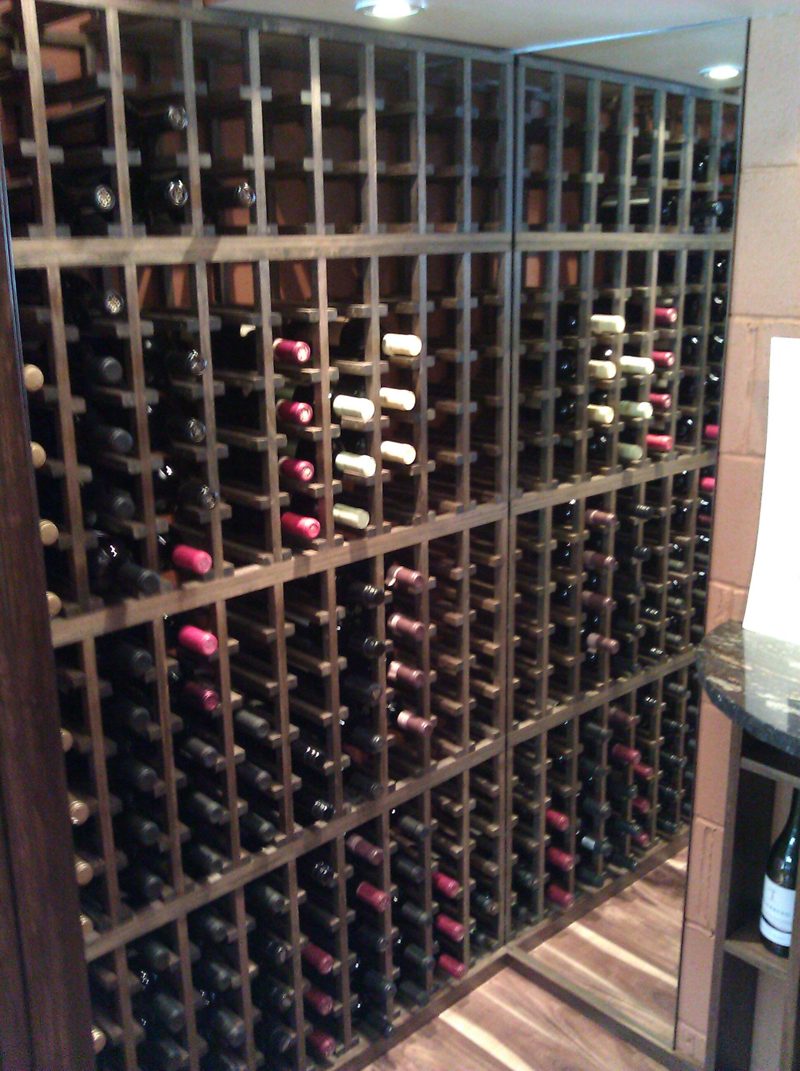 Floor-to-ceiling dark wood wine racks filled with bottles