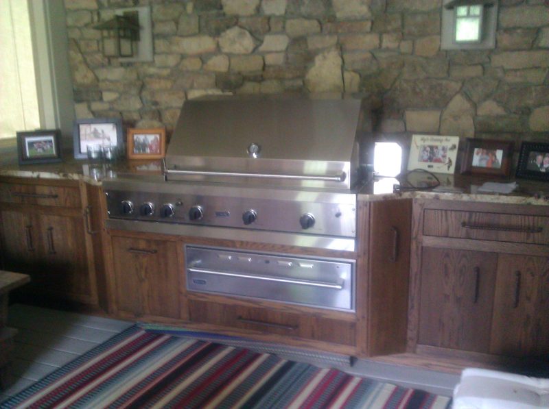 Outdoor kitchen with dark wood cabinets around a stainless grill