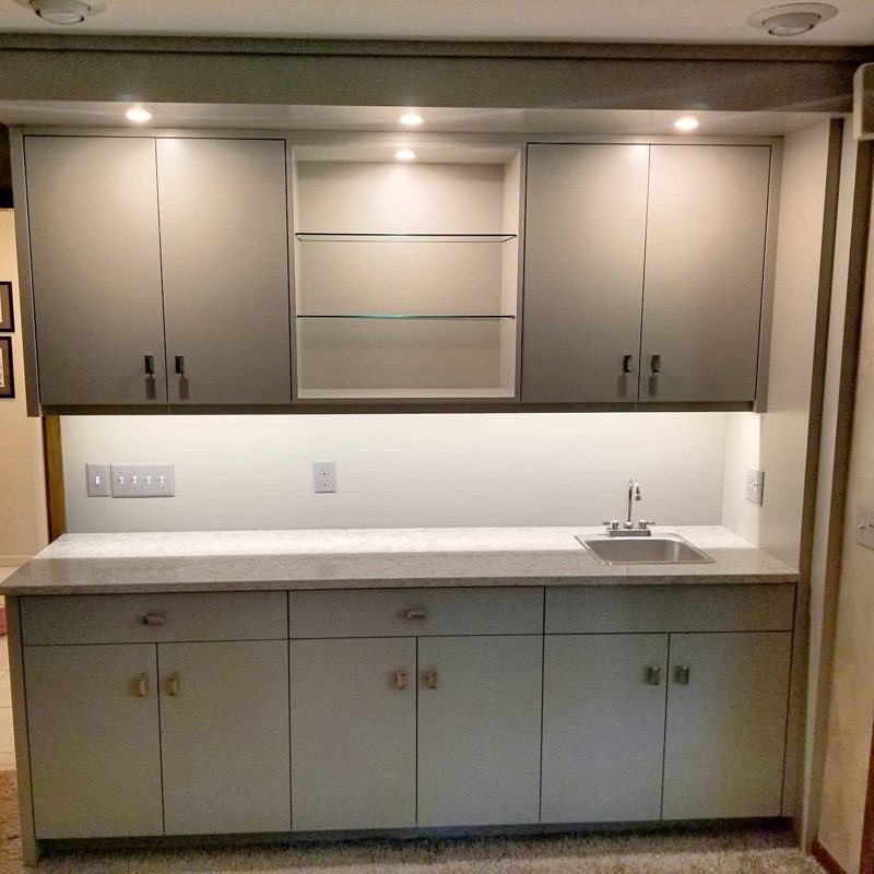 Straight view of a gray bar with glass shelves and a small sink
