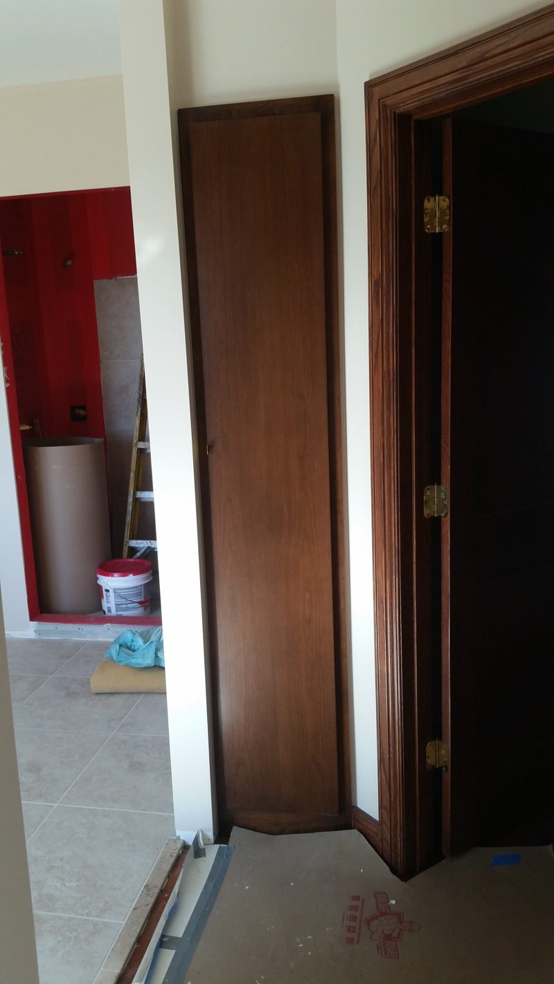 Dark wood door and matching trim installed in a bathroom under construction