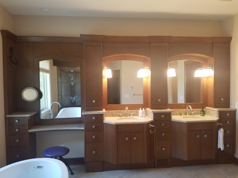 Dark cherry double vanity with arched mirror niches, a makeup desk, and tall towers
