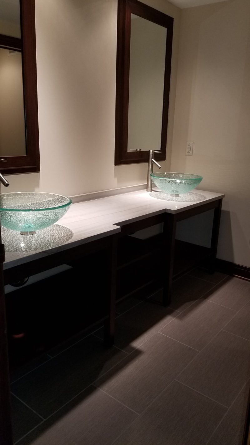 Open dark wood double vanity with glass bowl sinks on a pale countertop