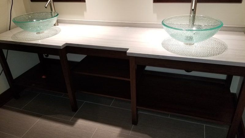 Long open console vanity with two glass vessel sinks and a lower shelf