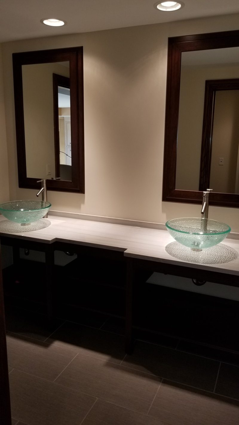 Dark wood double vanity seen from the side with two framed mirrors