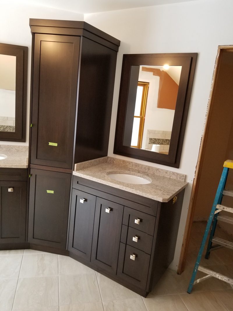 Side view of an espresso corner vanity with shaker doors and a linen tower