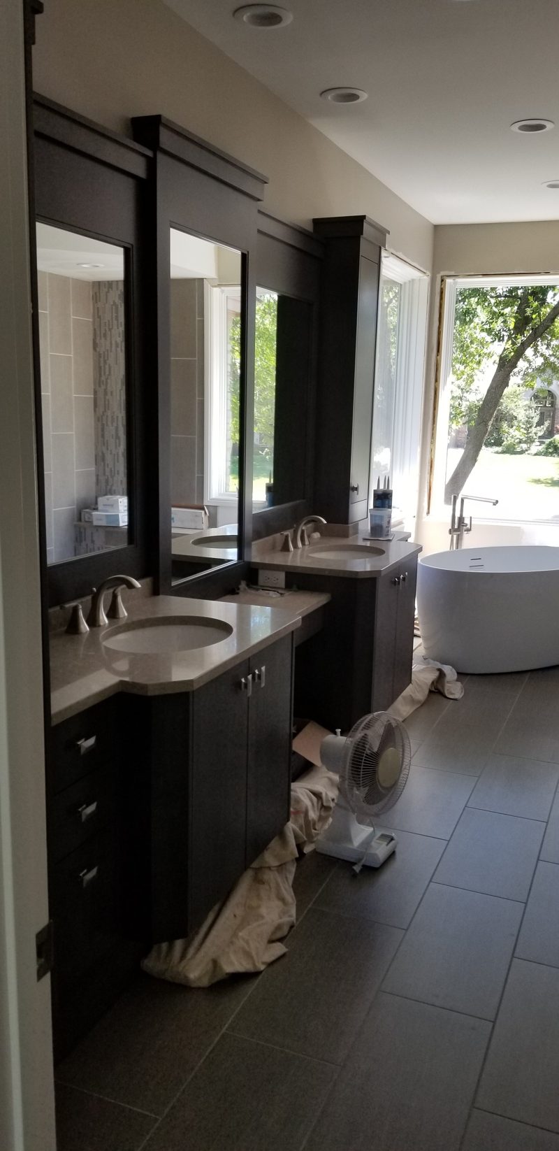 Dark vanity with tall mirrors and towers in a bathroom with a soaking tub