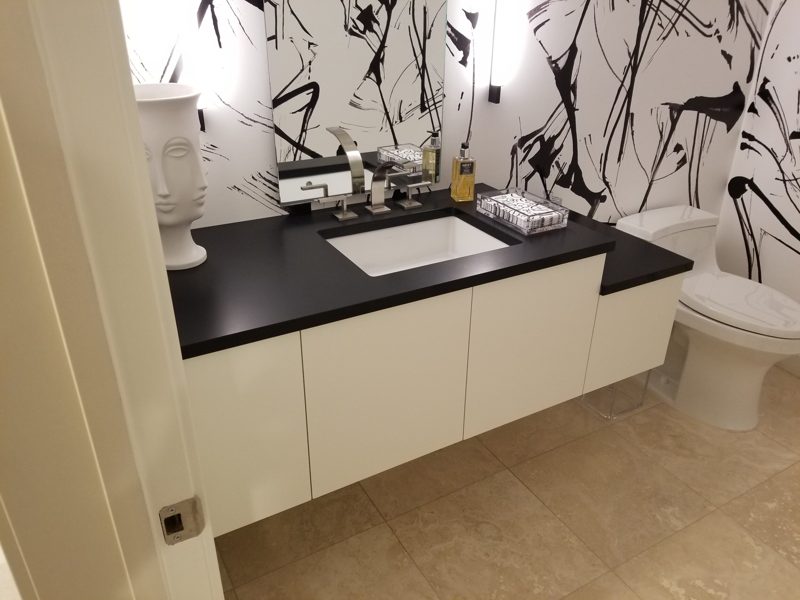 Floating white vanity with a black countertop against abstract black and white wallpaper