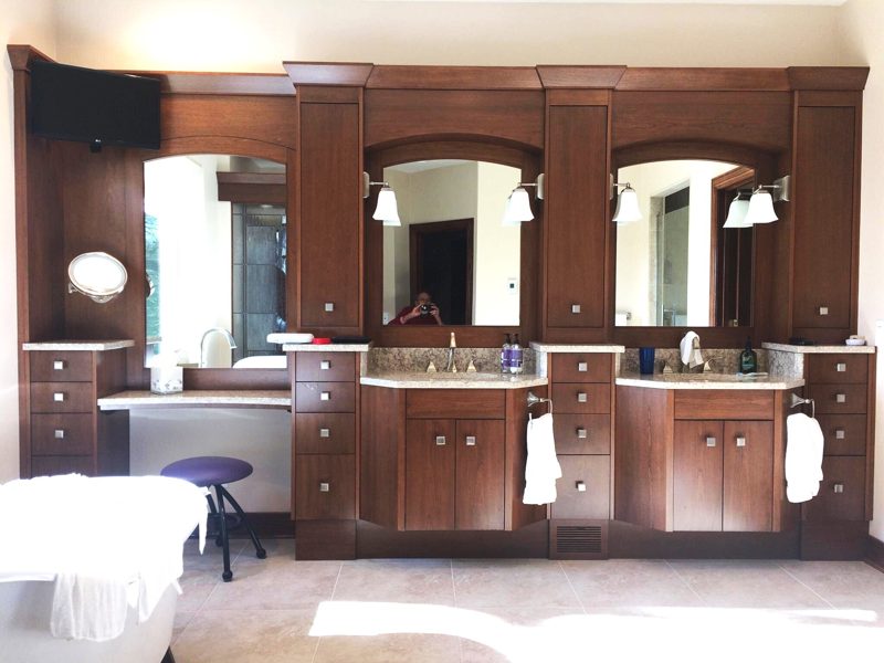 Dark cherry double vanity with arched mirrors, tall towers, and a makeup desk