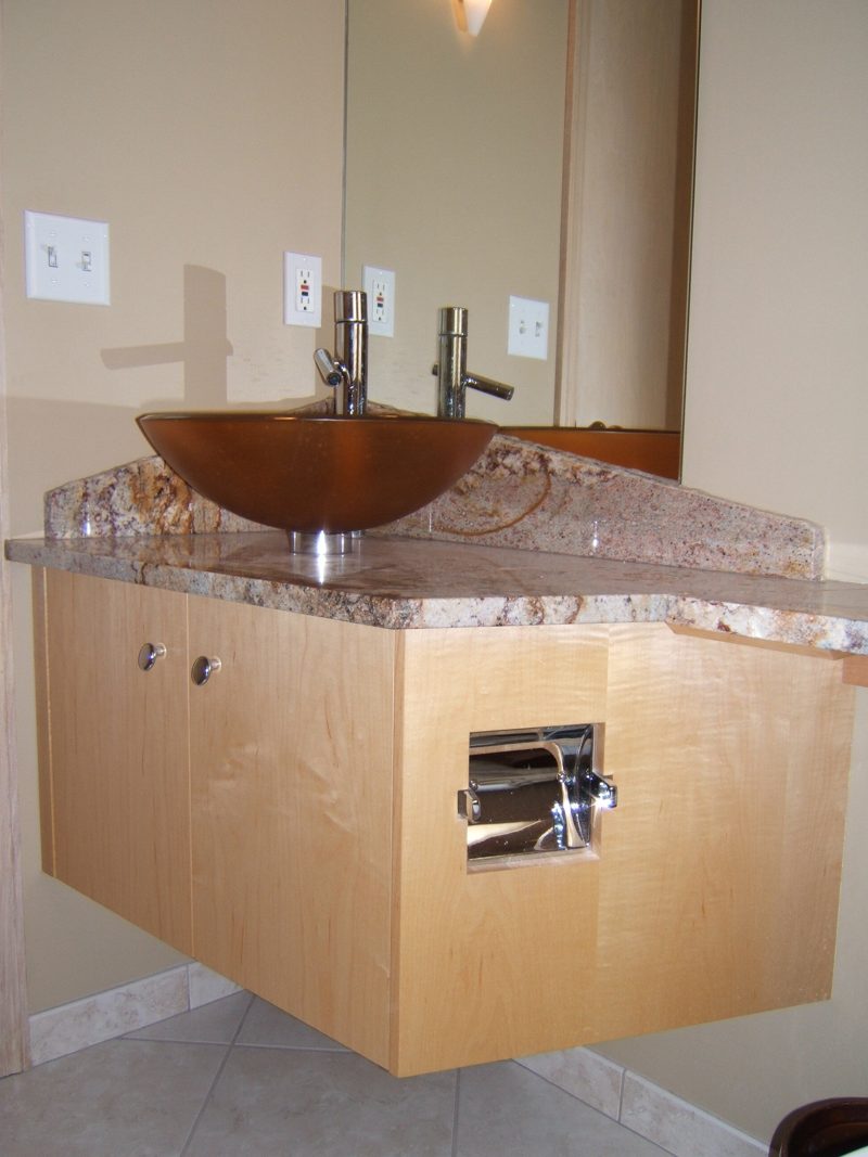 Floating maple vanity with an amber vessel sink and a built-in paper holder