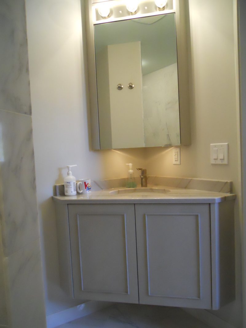 Small floating gray vanity with a marble top below a medicine cabinet