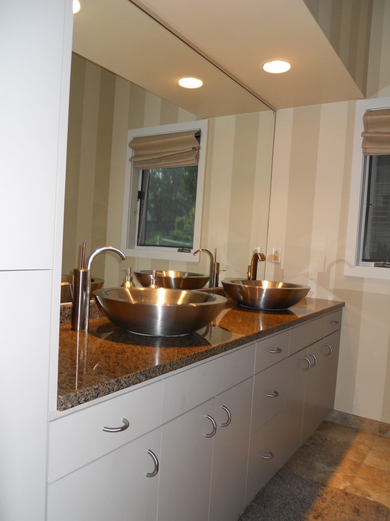 White vanity with a granite countertop and two stainless steel vessel sinks