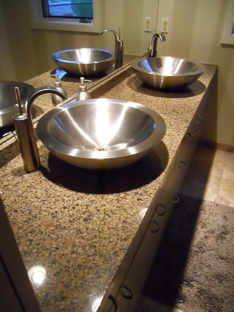 Close view of a steel vessel sink on a granite countertop