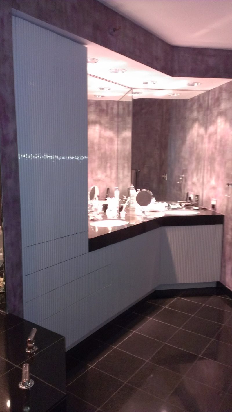 White ribbed tall cabinet and vanity in a bathroom with a lit soffit