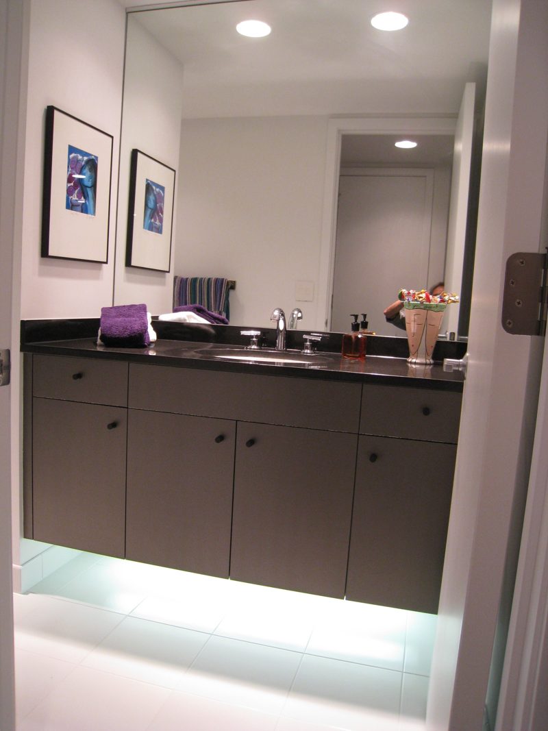 Gray vanity with a black countertop floating above an illuminated floor gap