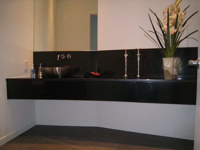 Floating black stone counter with a vessel sink and wall-mounted faucet
