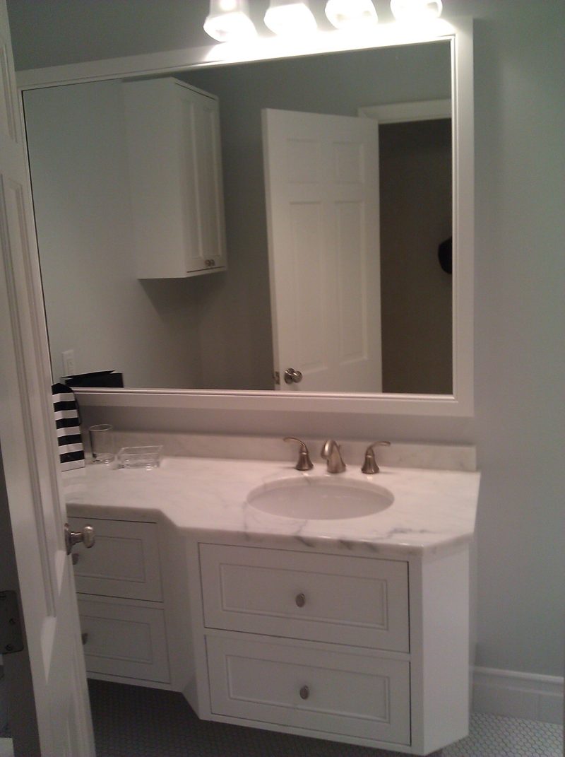 White vanity with angled drawers, a marble top, and a large mirror