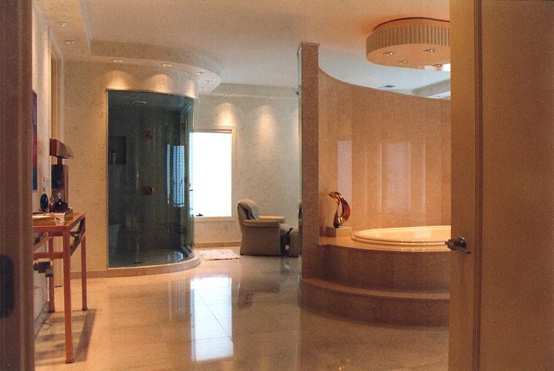 Large bathroom with a curved glass shower, round soaking tub, and polished floors