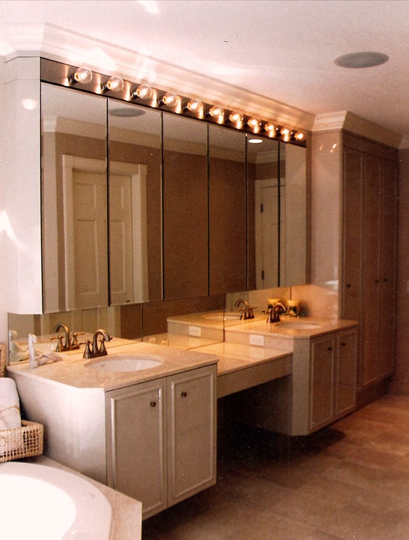Light vanity with a makeup desk, full wall mirror, and a row of vanity lights
