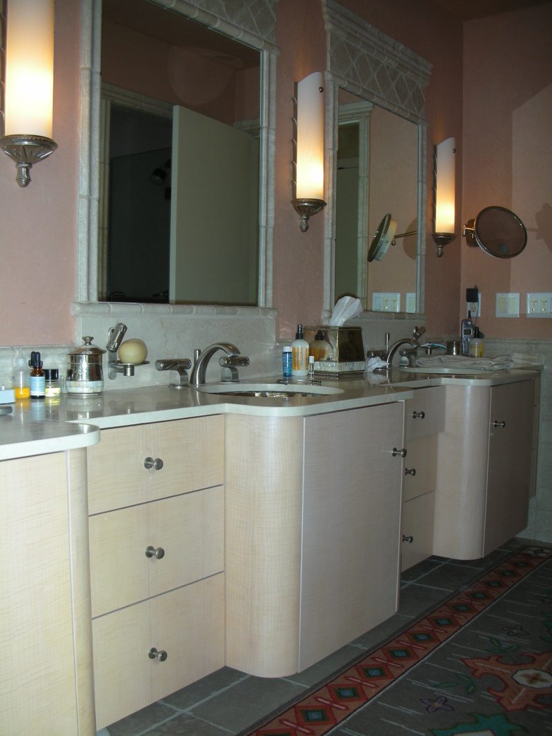 Light wood vanity with curved front drawers, a makeup area, and wall sconces
