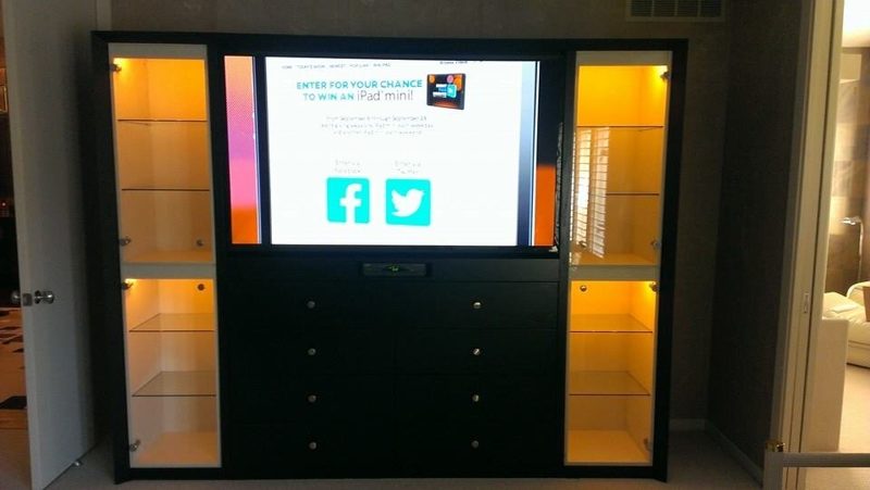 Black entertainment center with a TV, drawers, and lit glass-shelf side cabinets