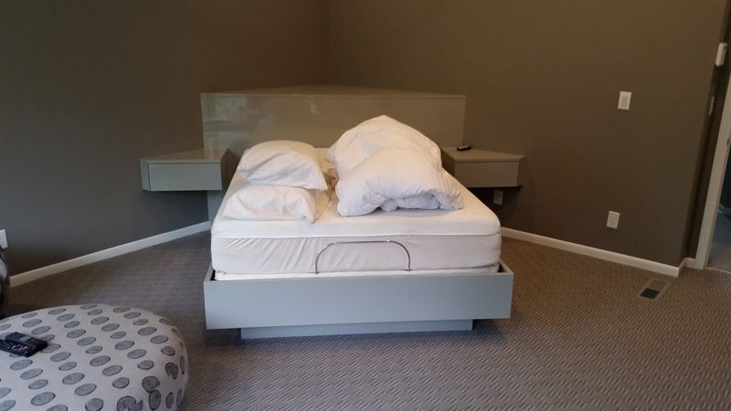 White platform bed with a pale headboard panel and floating nightstands