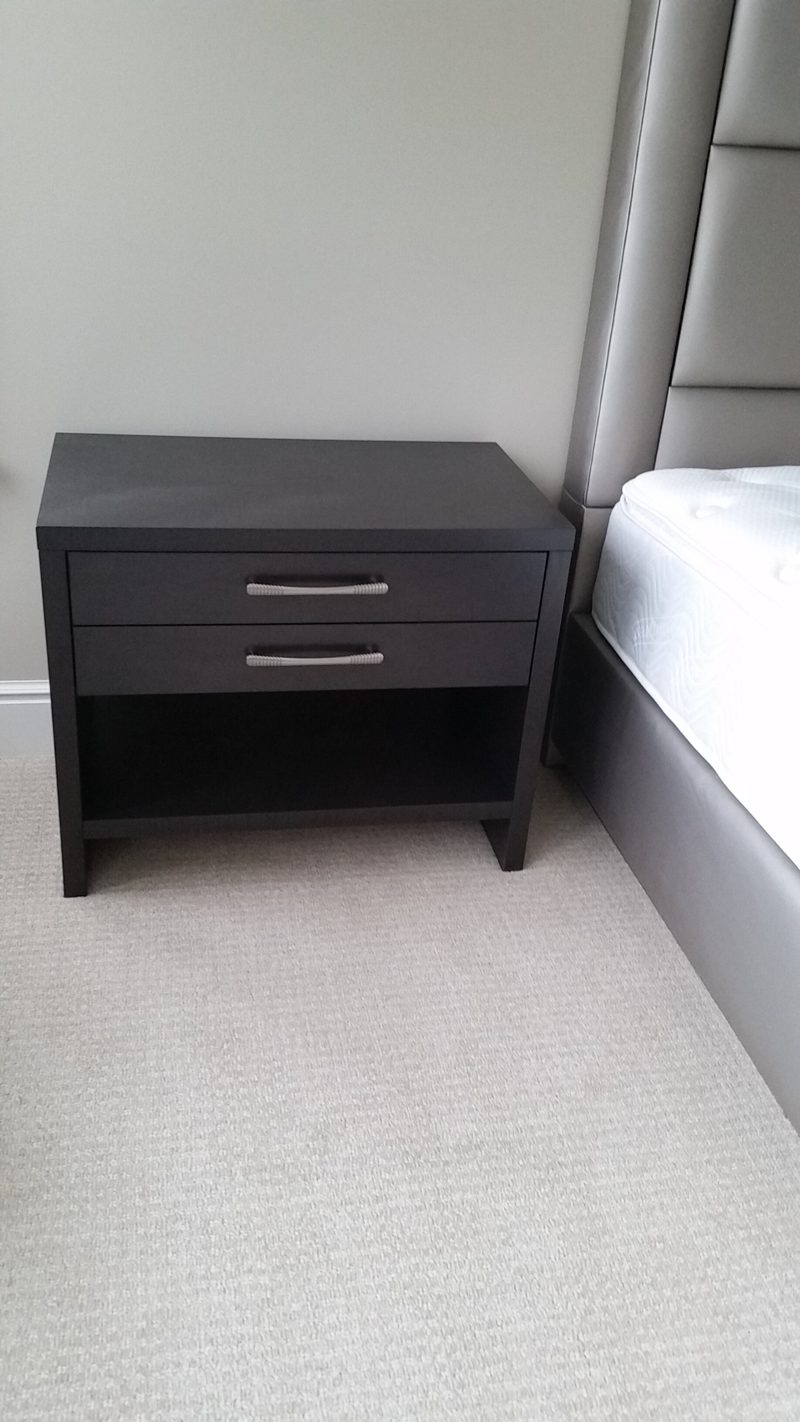 Dark gray nightstand with two drawers beside a bed