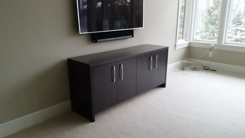 Dark gray media cabinet with two doors on each side below a wall-mounted TV