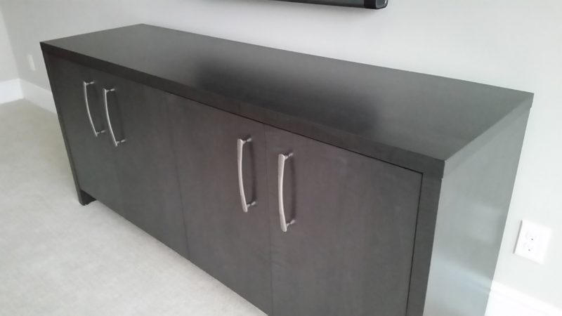 Angled view of a dark gray four-door cabinet with long bar pulls