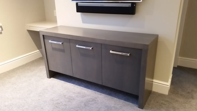 Dark gray media console with three doors below a wall-mounted TV
