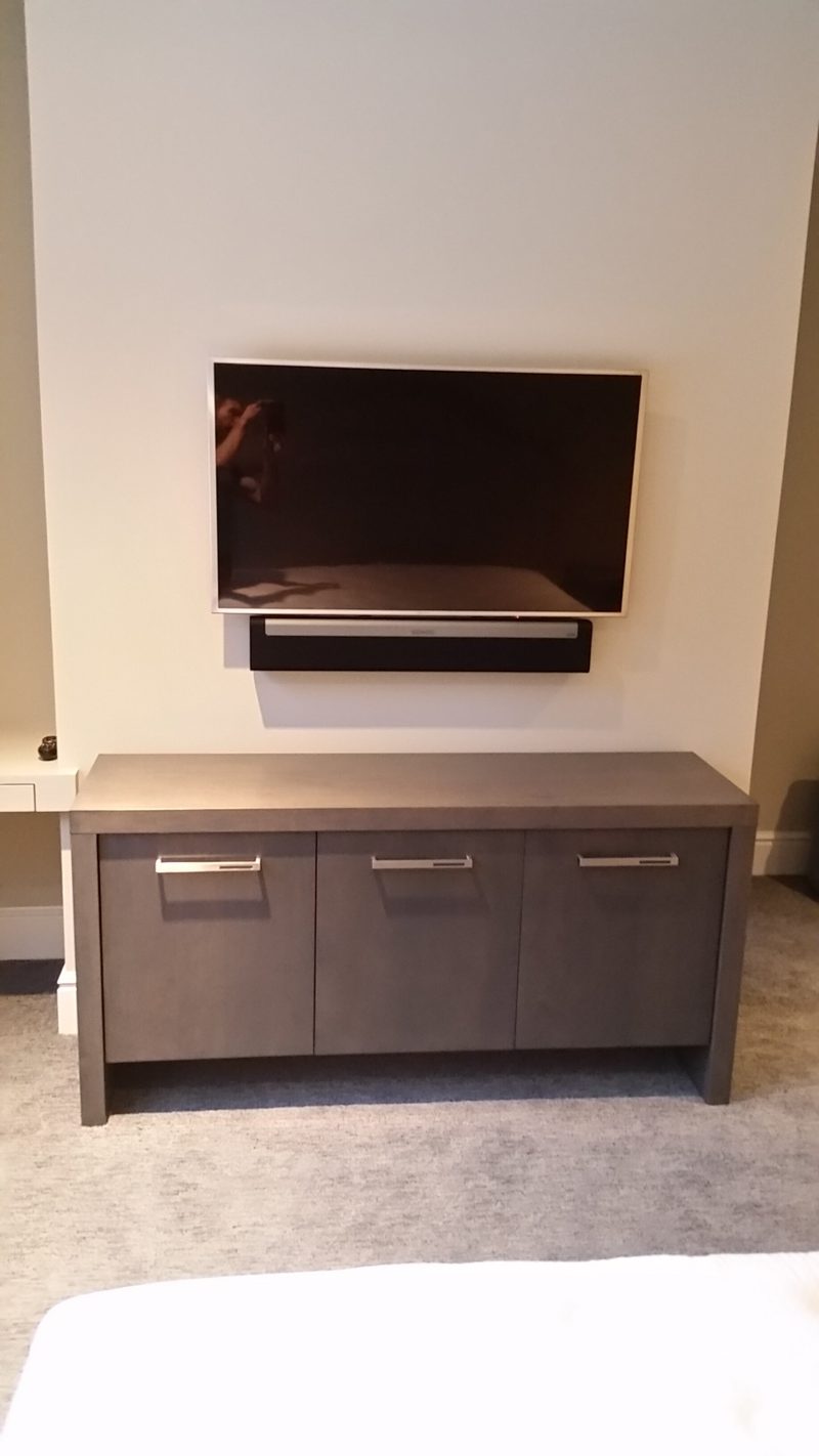 Dark gray media console beneath a wall-mounted TV and soundbar
